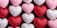 Glittery heart-shaped decorations in pink, red and white colors arranged on dark background for Valentine's Day, romance and love celebrations.