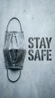 Protective face mask on gray concrete wall with Stay Safe stencil text, health awareness concept for pandemic prevention campaigns.
