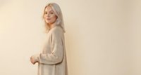 Young blonde Caucasian woman in beige sweater posing against neutral background for lifestyle and fashion photography projects.