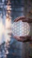 Hands protecting glowing flower of life sacred geometry symbol with soft bokeh background for spiritual wellness and meditation concepts.
