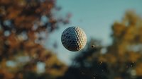 White golf ball floating in mid-air against blurred autumn background with bokeh effect and warm sunlight, capturing dynamic sports moment in motion.