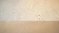 Textured cream wall with rough plaster finish above smooth beige surface, minimalist interior design background for modern home decor and architectural projects.