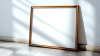 Empty golden frame leaning against white wall with natural window light shadow overlay, minimal modern home interior design element on wooden floor.