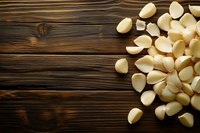 Fresh peeled garlic cloves scattered on rustic wooden table background for cooking and culinary preparations.