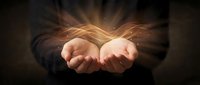 Cupped hands releasing golden energy waves with magical light rays emanating upward against dark background for spiritual and healing concepts.