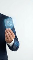 Businessman hand protecting glowing security shield with checkmark icon representing cybersecurity protection and data safety in corporate environment.