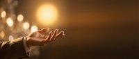 Caucasian male hand reaching toward glowing orb of light against warm bokeh background, symbolizing hope, spirituality, and aspiration for business and motivational content.