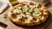 Freshly baked pizza with melted cheese, mushrooms, and fresh herbs on wooden serving board with olive oil and kitchen linens nearby.