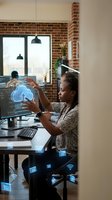 African American woman software developer working with cloud computing technology in modern office workspace with brick walls and digital interface.