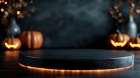 Illuminated black product display platform with glowing orange light and Halloween pumpkin decorations in dark moody background creates spooky atmosphere.