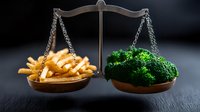 French fries and fresh broccoli balanced on vintage scale against dark background, representing food choices between healthy and fast food options.