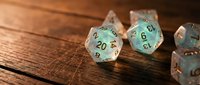 Polyhedral gaming dice set with turquoise and copper colors on wooden table surface for tabletop role-playing games and board game adventures.