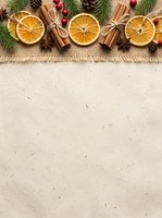 Dried orange slices, cinnamon sticks, evergreen branches, and red berries arranged on burlap fabric with copy space for holiday greeting cards, seasonal marketing, and festive design projects.