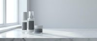 Minimalist skincare cosmetic bottles and jar on white marble surface with natural window light creating soft shadows for beauty product mockup.