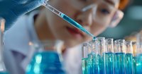 Asian female scientist in protective eyewear using micropipette to transfer blue liquid solution into test tubes in research laboratory setting for medical studies.
