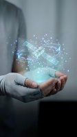 Hands holding holographic satellite with glowing particles and digital effects representing space technology, communication networks, and futuristic innovation concepts.