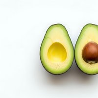 Fresh ripe avocado halves with pit on clean white background isolated for healthy cooking and nutrition design projects.