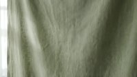 Soft sage green linen fabric texture with natural wrinkles and folds creating organic shadows and highlights for interior design and textile backgrounds.
