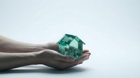 Hands holding small green house model representing real estate investment, property protection, home insurance, mortgage concept for financial planning.