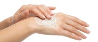 Hands applying white moisturizing cream or lotion on skin, isolated on white background. Suitable for skincare, cosmetics, beauty product marketing, and wellness advertising.