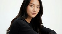 Young Asian woman in black hoodie with long dark hair posing confidently against neutral background for lifestyle and fashion content.