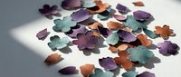 Colorful decorative flower petals scattered on white surface, isolated design elements for crafts, invitations, and artistic projects.