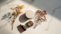 Luxury skincare cosmetics with dried flowers on marble surface creating elegant shadows for beauty and wellness branding.