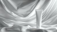 White cosmetic tube on elegant draped silk fabric background with soft folds and gentle shadows creating luxurious minimalist composition for beauty product presentation.