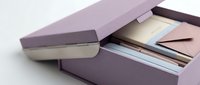 Purple cardboard box containing stack of printed photographs and documents for memory storage and organization projects.