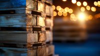 Rustic wooden wall with stone elements illuminated by warm string lights creating magical bokeh effect against dark blue evening background.