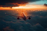 Commercial passenger aircraft flying above dramatic sunset clouds with orange and teal sky, rear view of modern airplane during flight at high altitude.