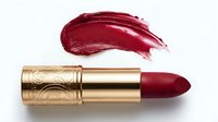 Deep burgundy lipstick with gold ornate tube and matching swatch stroke on white background. Cosmetics and beauty product photography for makeup advertising.