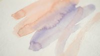 Abstract watercolor brush strokes in soft purple and peach tones on textured paper creating artistic background for creative projects.