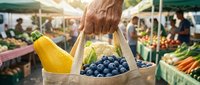 Shopper holding paper bag with fresh blueberries and yellow squash at farmers market with produce stands and customers in background.