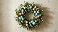 Easter wreath with pastel eggs and eucalyptus leaves on neutral background for spring holiday decoration and seasonal home decor projects.