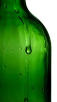 Close-up of green glass bottle with water droplets and condensation on white background, suitable for beverage, packaging, and product design projects.