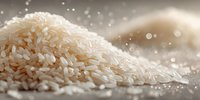 Raw white rice grains scattered on neutral surface with soft bokeh background, showcasing natural texture and culinary ingredient.