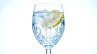 Glass of refreshing lemon water with ice cubes isolated on white background, perfect for beverage, wellness, and food photography projects.