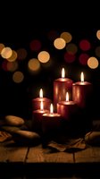 Red candles burning with warm bokeh lights creating cozy holiday atmosphere on rustic wooden surface for seasonal celebrations and home decor.