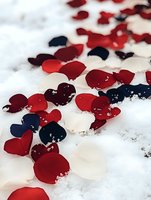 Red, white and navy blue heart confetti scattered on fresh snow creates romantic winter mood. For Valentine's Day, weddings, or patriotic celebrations.