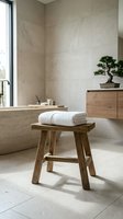 Modern minimalist bathroom interior with wooden stool, white towels, marble walls and natural lighting for spa-like home design and relaxation.