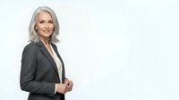 Mature woman with silver-gray hair, Caucasian ethnicity, wearing dark charcoal blazer over white shirt, professional business attire, isolated on white background for corporate and corporate headshot use.