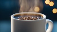 Steaming hot coffee in white ceramic mug with golden bokeh lights in dark background, close up view. Fresh morning beverage with aromatic foam.
