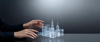 Businessman hands protecting holographic city skyline with skyscrapers on dark background representing urban development and real estate investment concepts.