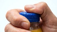 Hands holding blue and yellow bottle cap with liquid, isolated on white background for product packaging, cleaning supplies, or chemical container design use.