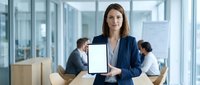 Woman professional holding tablet with blank screen in modern office environment with colleagues working in background.