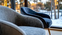 Modern gray and navy armchairs in cozy winter interior with panoramic window view of snowy forest at sunset, creating relaxing atmosphere for home decor.