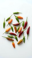 Colorful hot chili peppers scattered on white background. Fresh spicy vegetables in red, orange and green colors for cooking and culinary projects.
