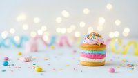 Colorful rainbow donuts with pink frosting and sprinkles on white surface with bokeh lights and party decorations for celebration dessert concept.