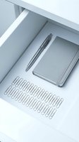 Minimalist office supplies in white drawer with gray notebook, pen and paper clips for workspace organization and productivity.